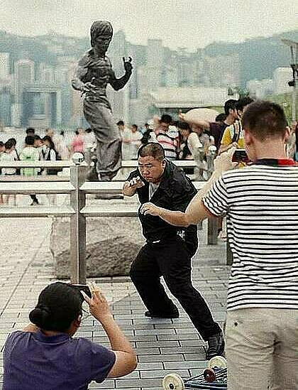 Một người đàn ông đang bắt chước bức tượng của huyền thoại võ thuật Lý Tiểu Long trên Đại lộ Ngôi sao của Hong Kong. Ảnh: Stuart Heaver/SCMP